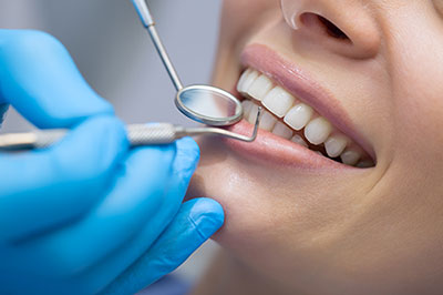 A dental professional using a drill on a patient s teeth during a dental procedure.