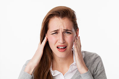 The image features a woman with her hand on her head, appearing to be experiencing discomfort or pain, possibly due to an ear infection or similar health issue.