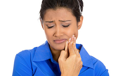 The image features a woman with her mouth open, possibly expressing surprise or concern, holding her finger near her teeth, which are visible, suggesting she might be examining them or experiencing pain.