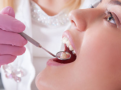 The image depicts a dental professional, likely a dentist, performing a procedure on a patient s mouth with a dental drill.