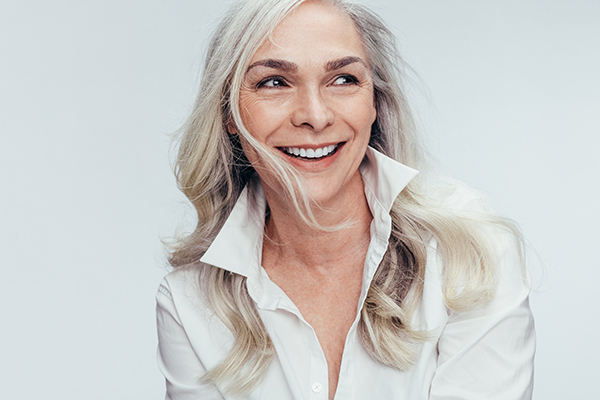 A middle-aged woman with short hair and a neutral expression is posing for a portrait against a white background.