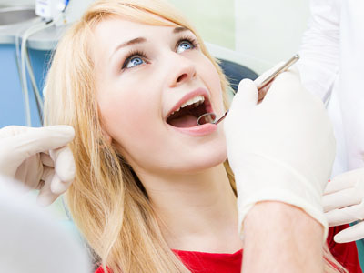 A woman receiving dental care with a smile on her face while wearing protective eyewear.