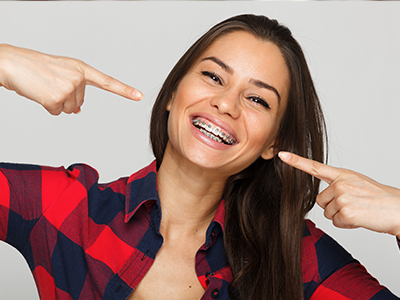 A woman pointing at her teeth with a playful expression.